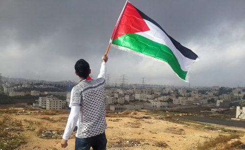 Un uomo sventola la banidera palestinese in Palestina