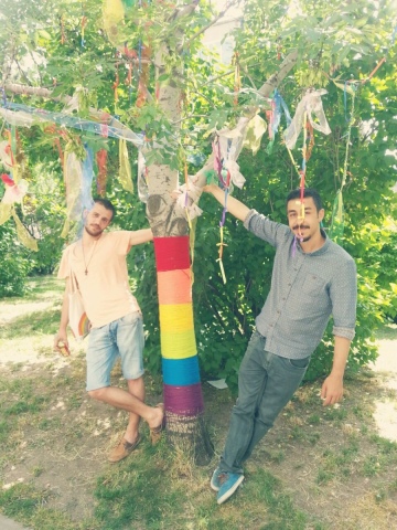 due uomini abbracciati a un albero con bandiera arcobaleno
