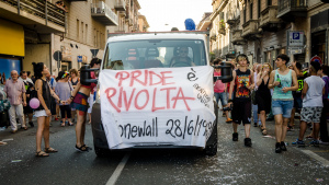 Foto di un pride: carri persone e striscioni su stonewall